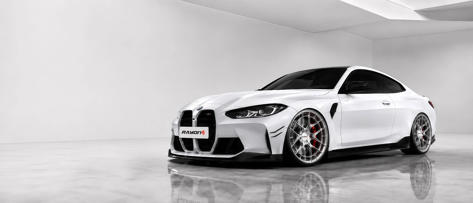 White performance coupe fitted with RAYONE alloy wheels in a refined studio space